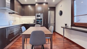 A modern kitchen with dark wood cabinets, stainless steel appliances, and a wooden dining table with chairs.