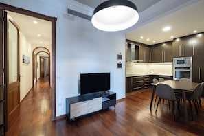 Una cocina moderna con armarios oscuros, microondas integrado y una zona de comedor con mesa y sillas.