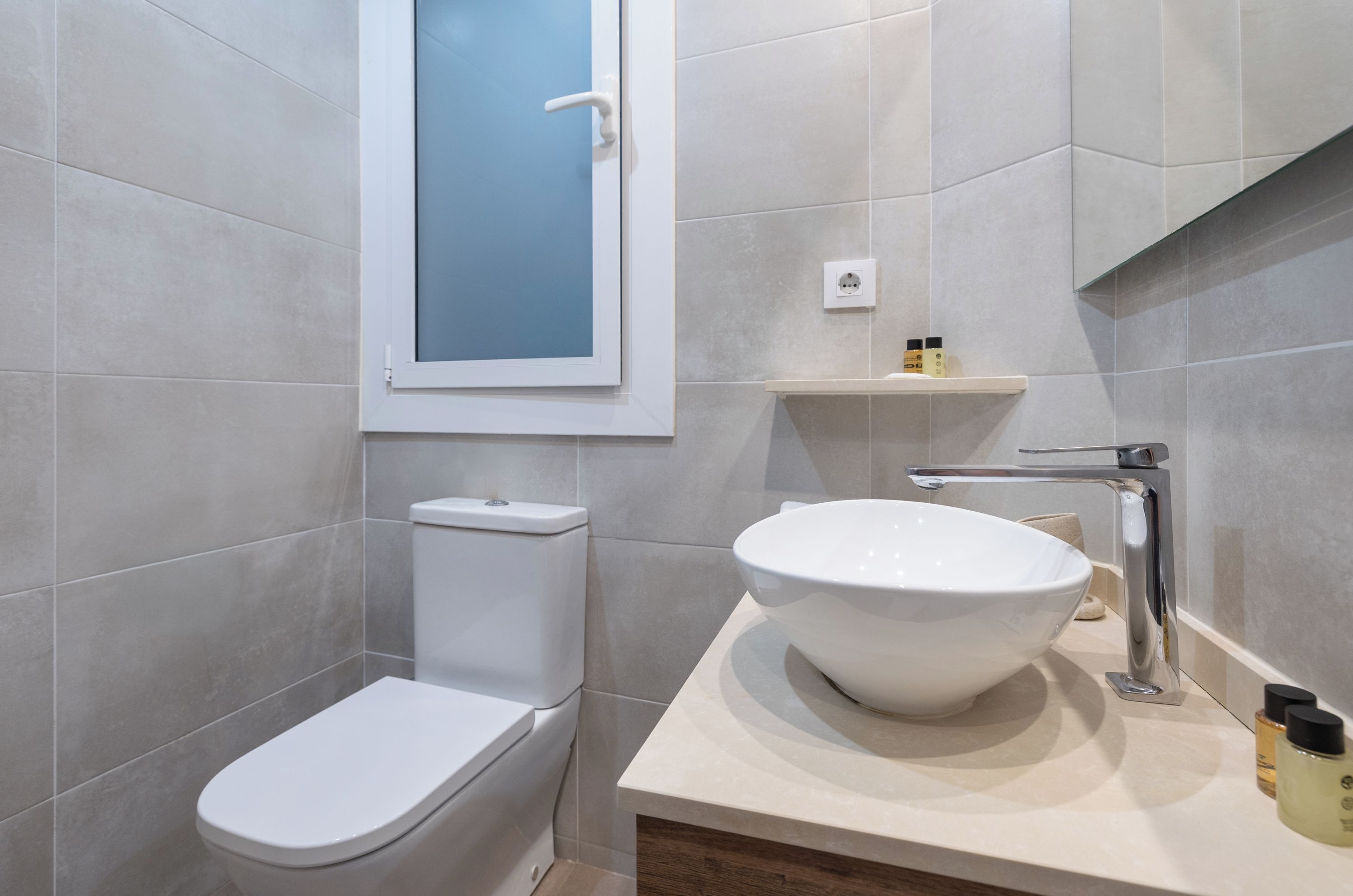 Een moderne badkamer met toilet, wastafel met kom en een douchecabine.