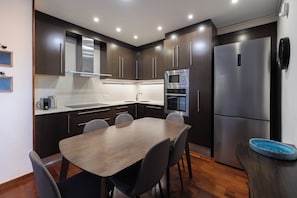 Una cocina moderna con armarios de madera oscura, electrodomésticos de acero inoxidable y una mesa de comedor con sillas.