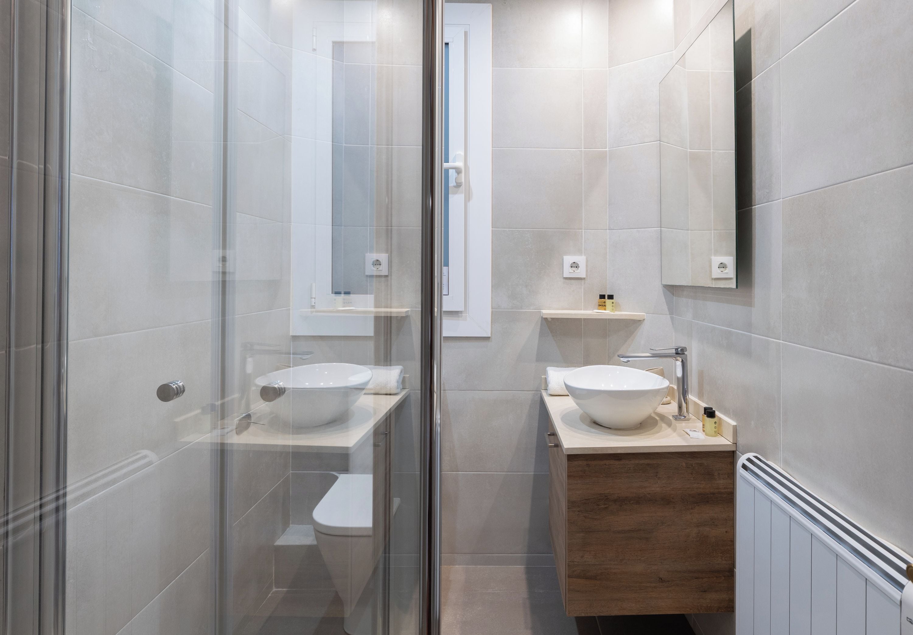 Une salle de bain moderne avec deux vasques, une douche à l’italienne en verre et un meuble-lavabo en bois.