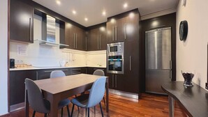 A modern kitchen with dark wood cabinets, stainless steel appliances, and a wooden dining table with chairs.