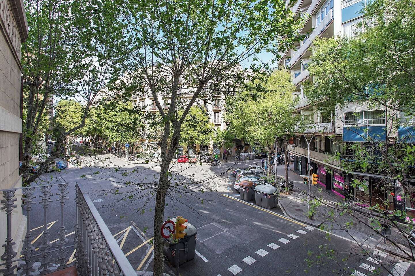 Une vue de rue avec des bâtiments, des arbres et des voitures garées.