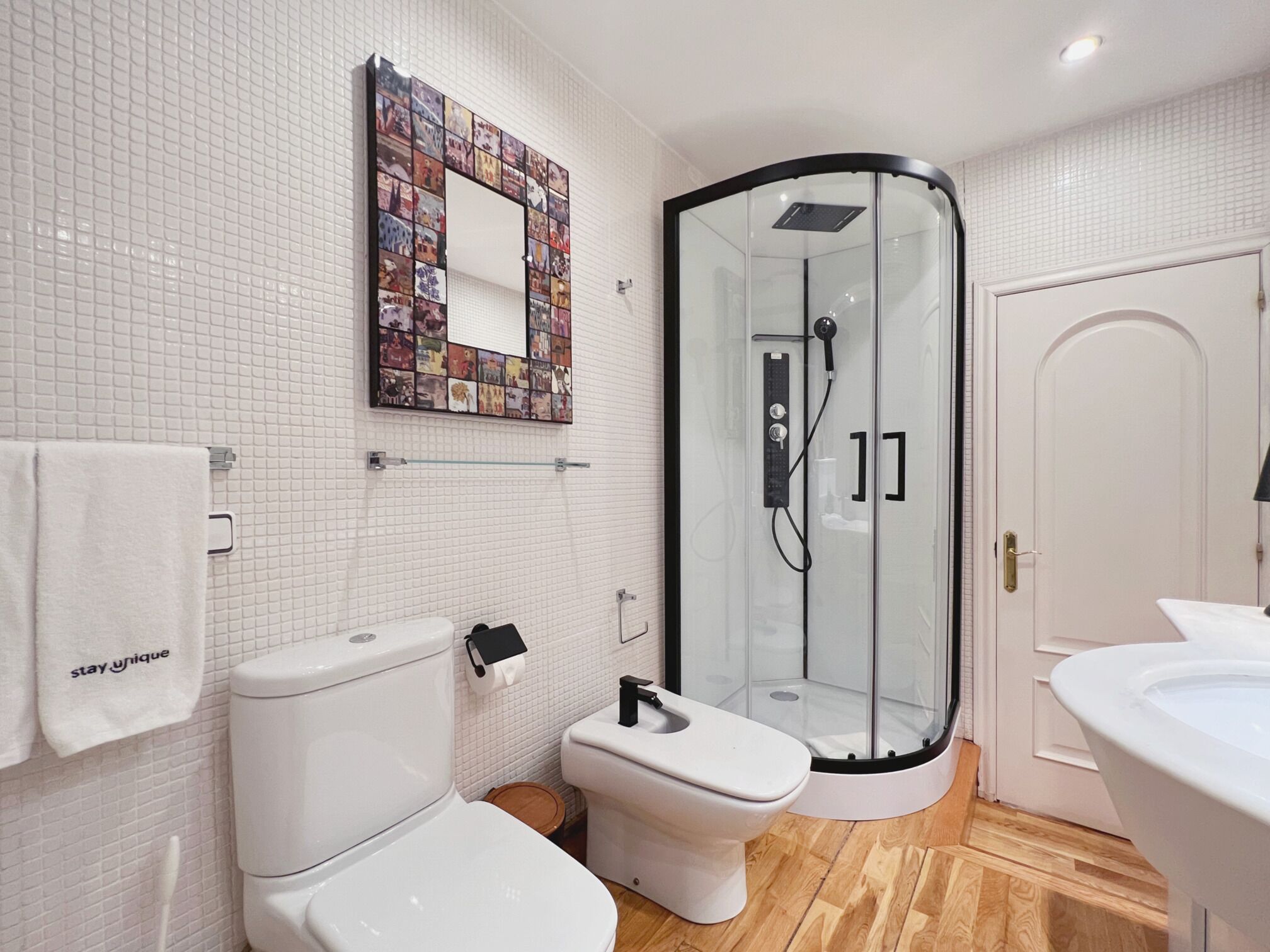 A modern bathroom with a glass shower enclosure, a toilet, and a sink.