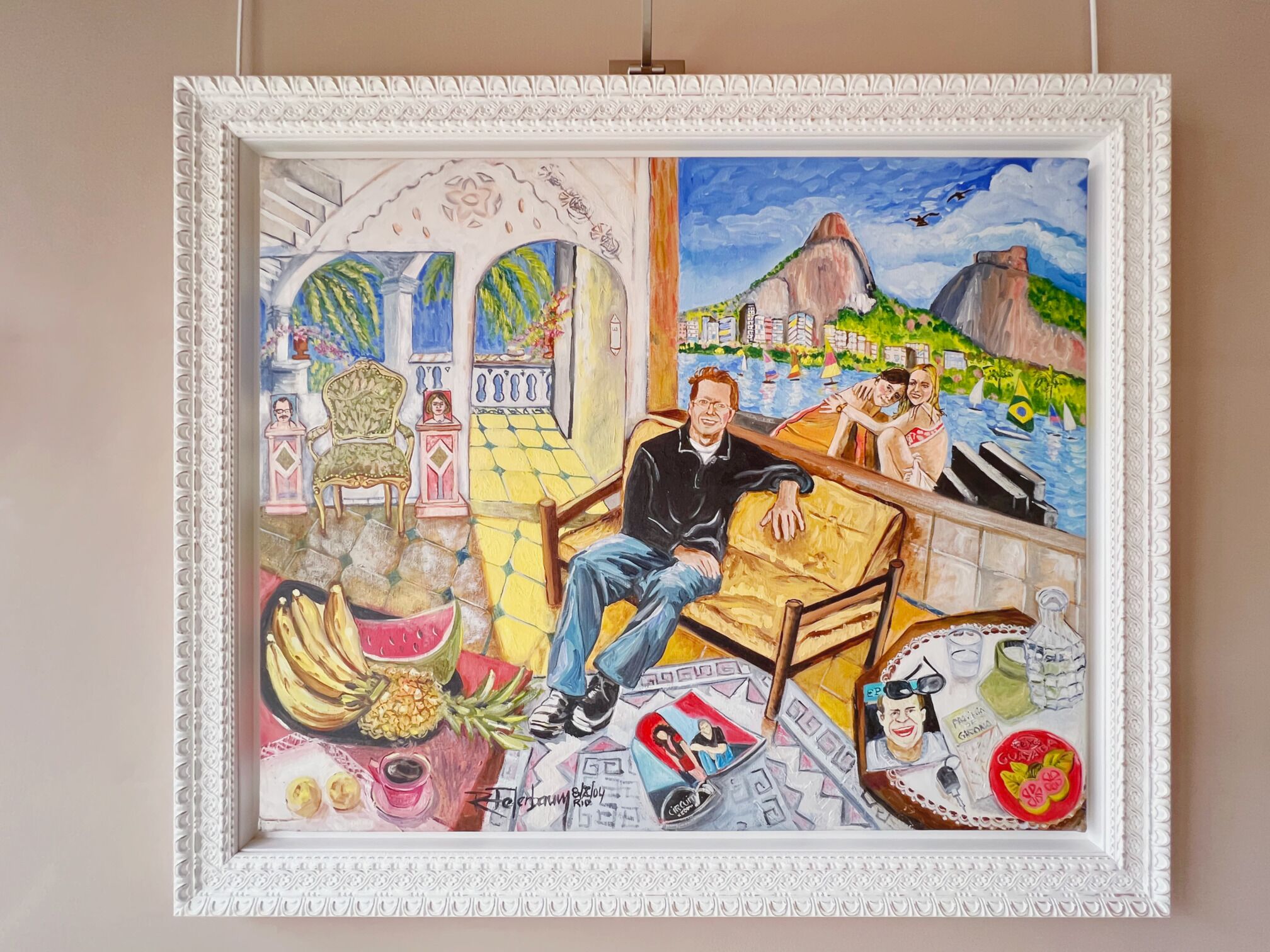 A framed painting depicting a man sitting on a couch, a table with drinks, and a window view of a cityscape with boats.