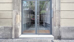 A modern building entrance with a glass door and a small step leading up to it.