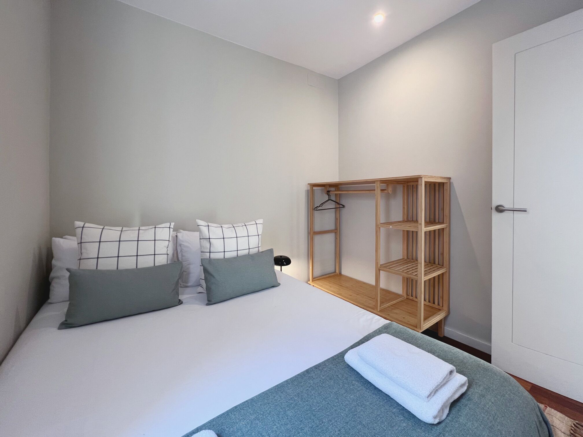 A bedroom with a bed, a wooden wardrobe, and a bedside table.