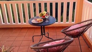 A balcony with a round table, two wicker chairs, and a potted plant. - Stay U-nique Apartments Benajarafe (Marbella)