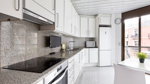 Une cuisine moderne dotée de plans de travail en granit, de meubles blancs, d’un four encastré et d’un micro-ondes.