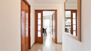 Un couloir avec des portes en bois et un grand miroir sur le côté droit.