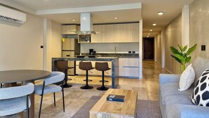 Una cocina moderna con una isla central, taburetes de bar y una mesa de comedor con sillas.
