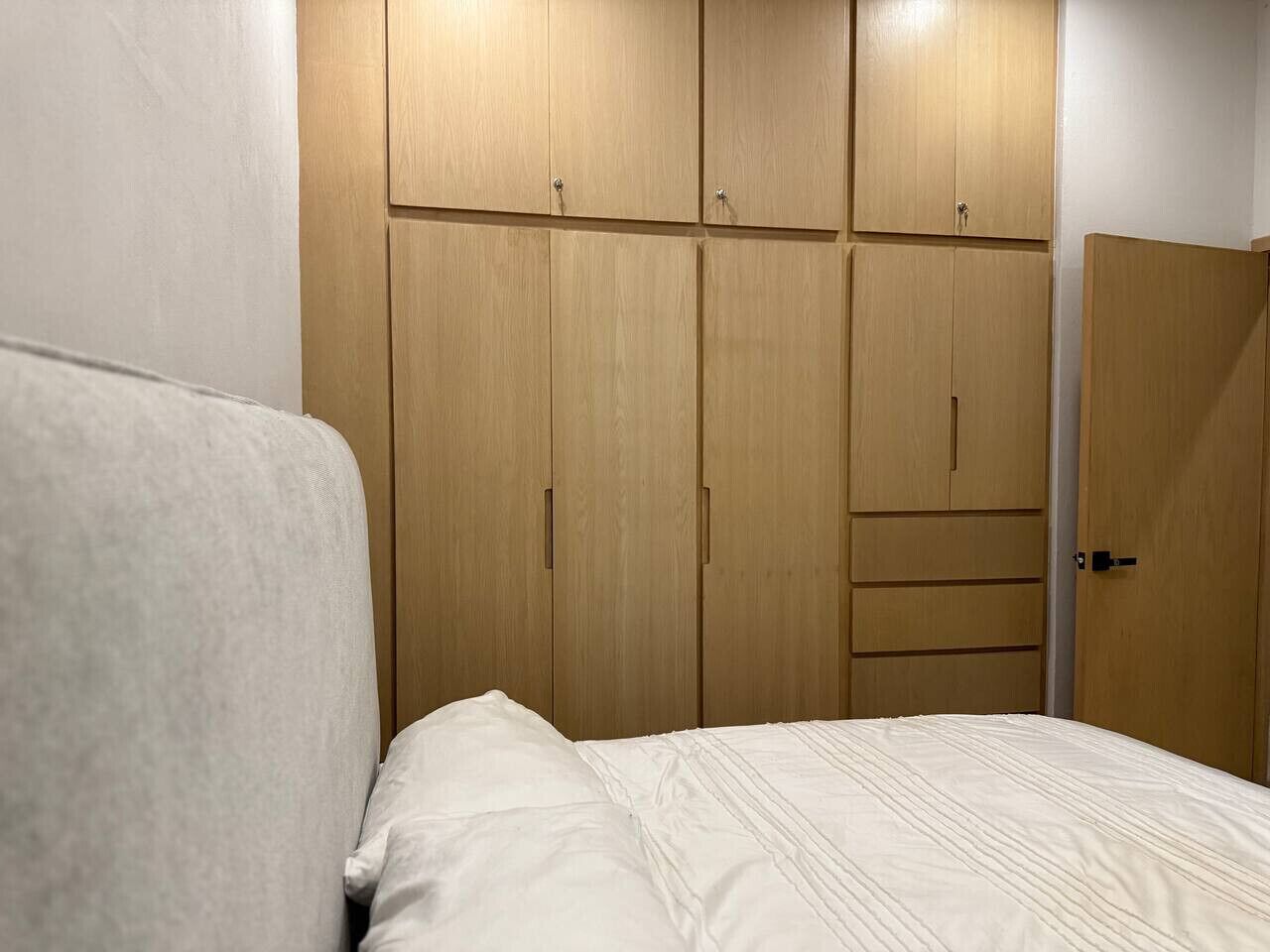 A bedroom with a bed, a wardrobe with multiple compartments, and a door.