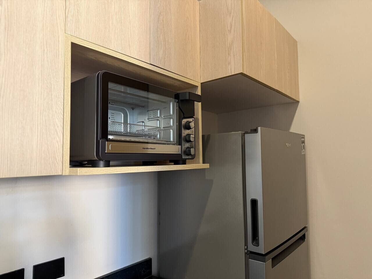 A kitchen with a built-in toaster oven and a stainless steel refrigerator.