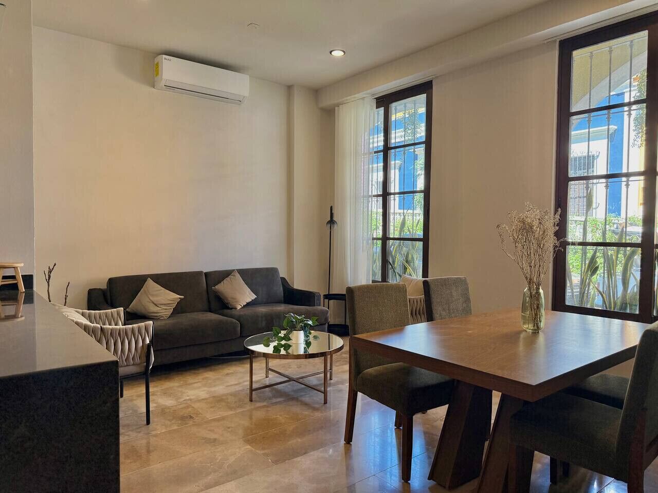 A modern living room with a sofa, coffee table, and dining table.
