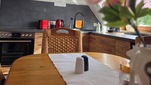 A modern kitchen with a built-in oven, a coffee machine, and a hanging light fixture.