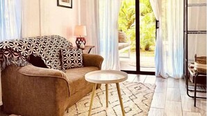 A cozy living room with a patterned sofa, a small round table, and a view of greenery outside. - La Prometida - House Marea (Puerto Viejo)
