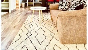 A spacious living area with a high ceiling, a ceiling fan, a kitchen in the background, and a patterned rug on the floor. - La Prometida - House Marea (Puerto Viejo)