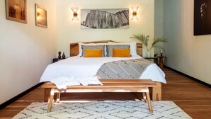 A bedroom with a bed, bedside tables, a bench, a rug, and wall-mounted artwork.