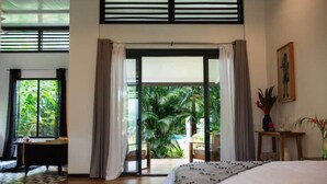 Un dormitorio con una cama grande, vista a una piscina y puerta corrediza que da a un espacio al aire libre.