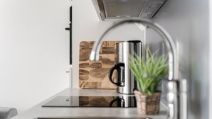 A modern kitchen with a stainless steel coffee maker, a sink, and a wooden backsplash. - Come in! `Wallesmanni` Best location in Tampere! (Tampere)