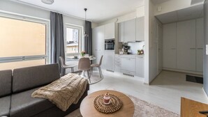 Een modern appartement met een woonkamer, eetgedeelte, keuken en een groot raam.