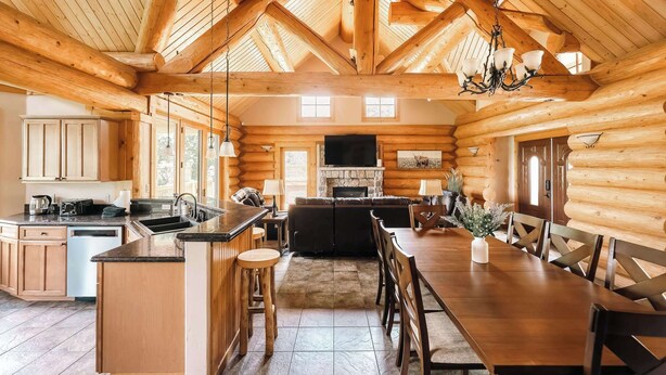 Ein Holzblockhaus-Interieur mit Küche, Essbereich und Kamin.