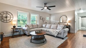 A spacious living room with a sectional sofa, a round coffee table, and a ceiling fan.