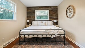A bedroom with a bed, a ceiling fan, a window, a clock, and a rug.