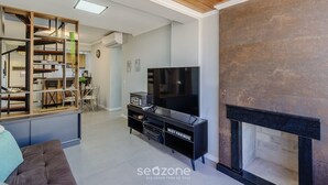 Una sala de estar moderna con televisor de pantalla plana, chimenea y comedor con sillas y mesa.