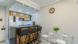 Una cocina moderna con barra, una mesa de comedor y sillas, y un reloj en la pared.