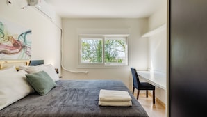 A bedroom with a bed, pillows, a desk, and a window. - Cozy and Well-located Apartment in POA - Rfa303 (Porto Alegre)