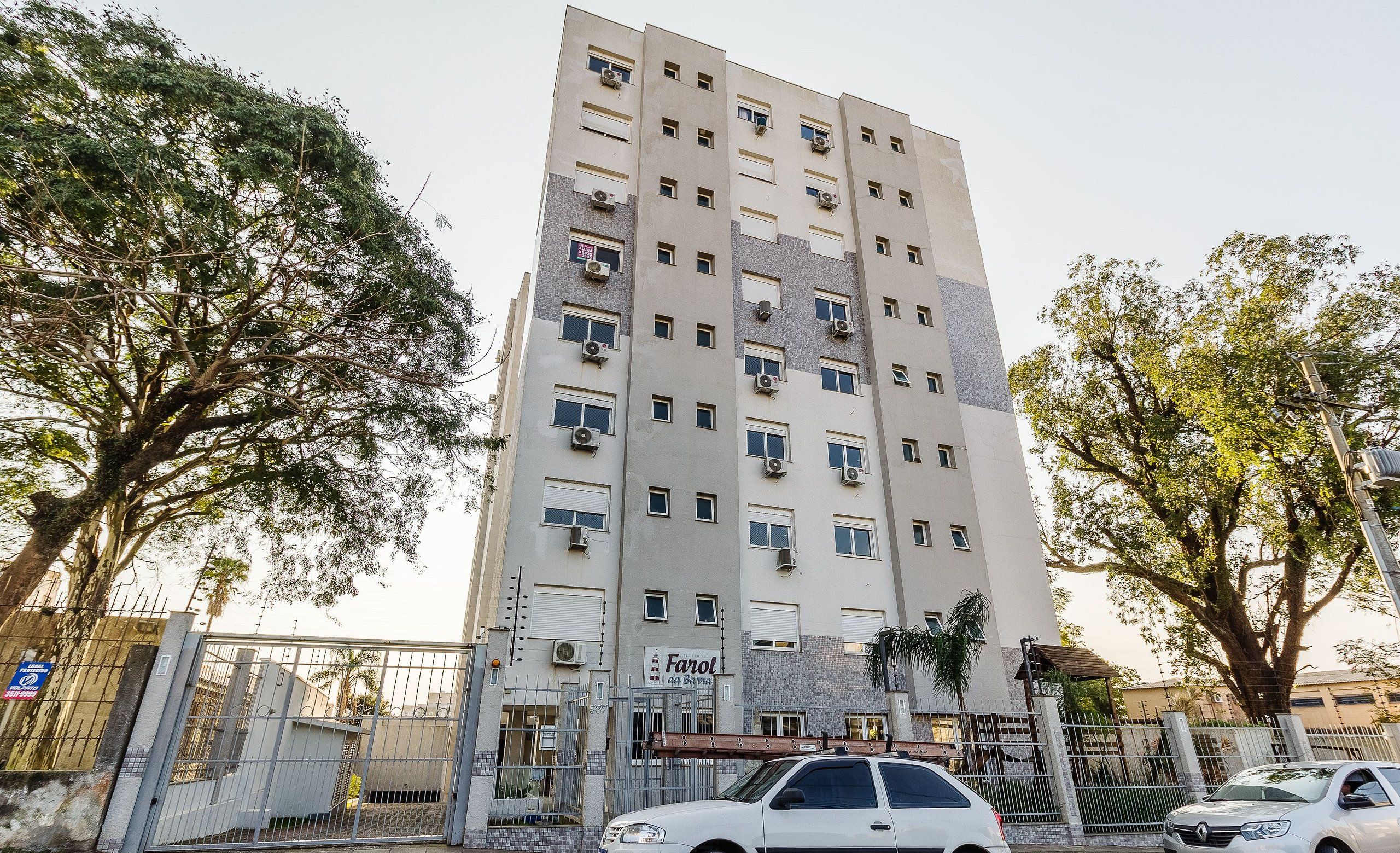 A multi-story building with a flat facade, air conditioning units, and a gated entrance.