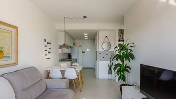 Uma sala de estar moderna com sofá, televisão e área de jantar.