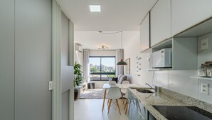 A modern kitchen with a large window, a dining area, and a view of the city. - Lindo Apto em Cond. c\/ Piscina e Garagem RPF0605 (Porto Alegre)