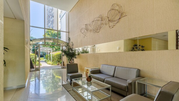 A modern lobby with a glass coffee table, a sofa, and a potted plant. - Beautiful Apartment With Barbecue in PoA Rps0460 (Porto Alegre)
