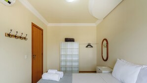 A hotel room with a bed, a wooden door, a coat rack, a mirror, and a white bedside table. - Elegant Apartment for Couples in Poa-rs Urb1110 (Porto Alegre)