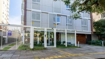 Um edifício moderno com entrada gradeada, área externa coberta e um caminho pavimentado.