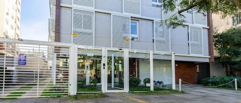 A modern building with a gated entrance, a covered outdoor area, and a paved walkway.