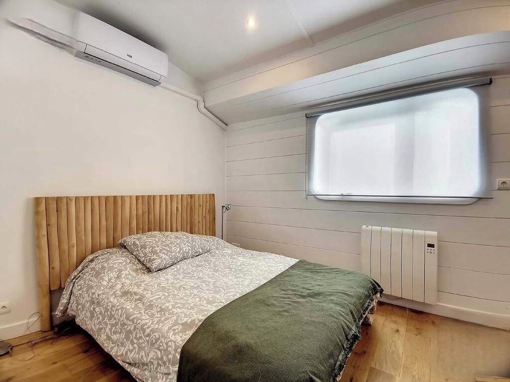 Une chambre à coucher avec un lit, une fenêtre, un climatiseur et un radiateur.