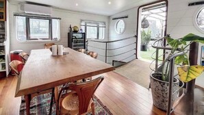 A modern interior with a wooden dining table, chairs, and a large potted plant. - Maison sur l'eau 3 chambres & Terrasse Proche Paris center (Villeneuve-la-Garenne)