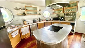 A compact kitchen with a central island, built-in microwave, and wooden cabinets. - Maison sur l'eau 3 chambres & Terrasse Proche Paris center (Villeneuve-la-Garenne)