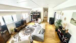 A spacious living area with a sofa, a TV, a bookshelf, and a dining table. - Maison sur l'eau 3 chambres & Terrasse Proche Paris center (Villeneuve-la-Garenne)
