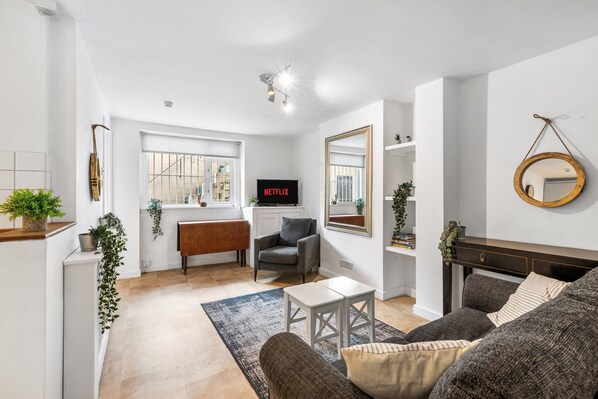 A modern living room with a grey sofa, a white coffee table, and a TV displaying 'NETFLIX'.