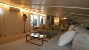 A spacious living room with a large sofa, a glass coffee table, and a floor lamp.
