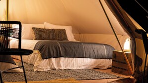A tented accommodation with a bed, a chair, a suitcase, and a rug. - ENDEMICA GLAMP RESORT (Cuatro Cienegas)