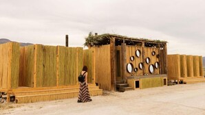 A rustic wooden structure with a thatched roof, circular mirrors on the walls, and a person standing in front. - ENDEMICA GLAMP RESORT (Cuatro Cienegas)