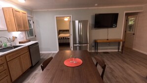 Une cuisine moderne avec des meubles en bois, un réfrigérateur en acier inoxydable et une table à manger avec des chaises.