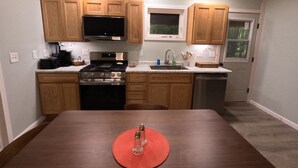 Une cuisine moderne avec des meubles en bois, des appareils en acier inoxydable et une table à manger agrémentée d’un set de table rouge.