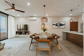 A modern dining area with a wooden table, chairs, and pendant lighting. - Arch View Condo Cabo San Lucas • 4th Floor Rooftop Pool | 403 (Cabo San Lucas)