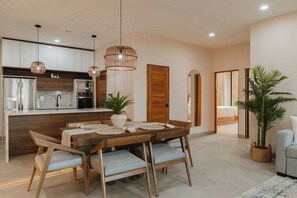 A modern kitchen with a central island, wooden chairs, and pendant lighting.